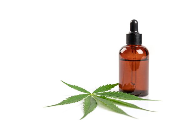 Hemp leaf with bottle of CBD oil
