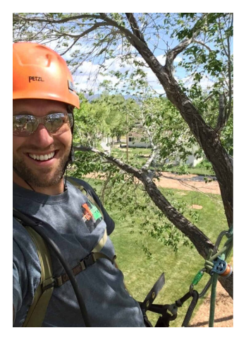 SuperTrees team member smiling while tree pruning.